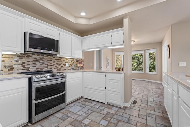 kitchen featuring appliances with stainless steel finishes, decorative backsplash, and white cabinets