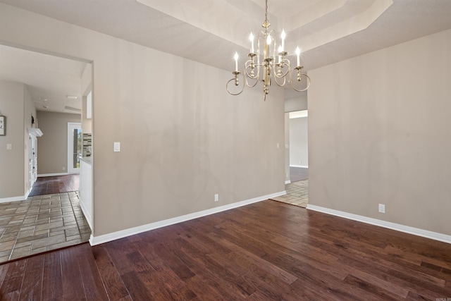 empty room with a notable chandelier and dark wood-type flooring