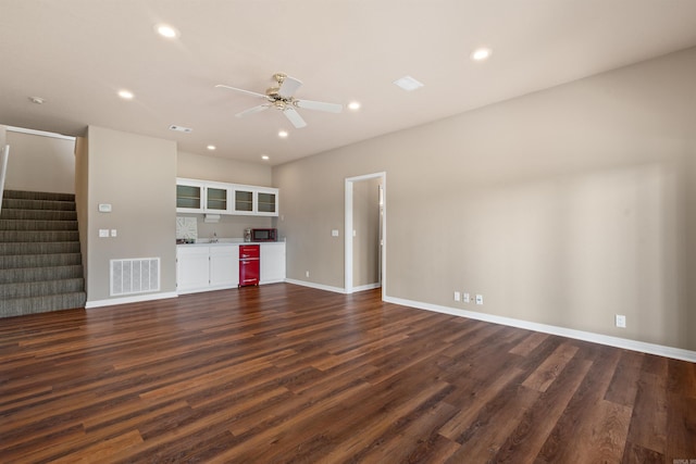 unfurnished living room with ceiling fan and dark wood-type flooring