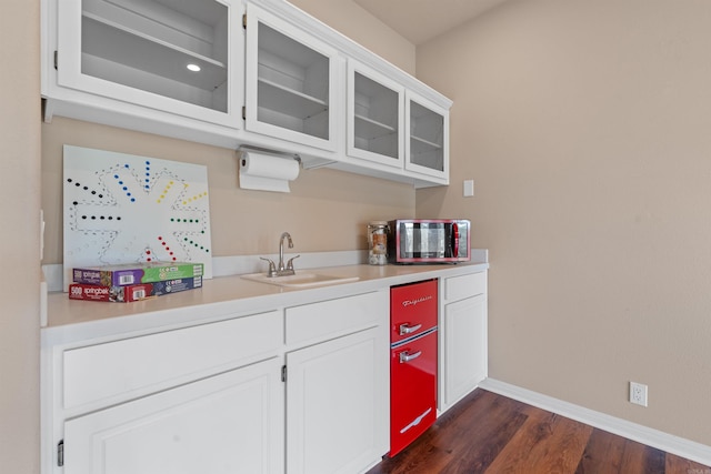 bar featuring dark hardwood / wood-style floors, sink, and white cabinetry