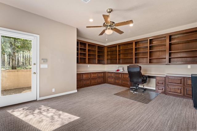 unfurnished office featuring ceiling fan, built in desk, and carpet