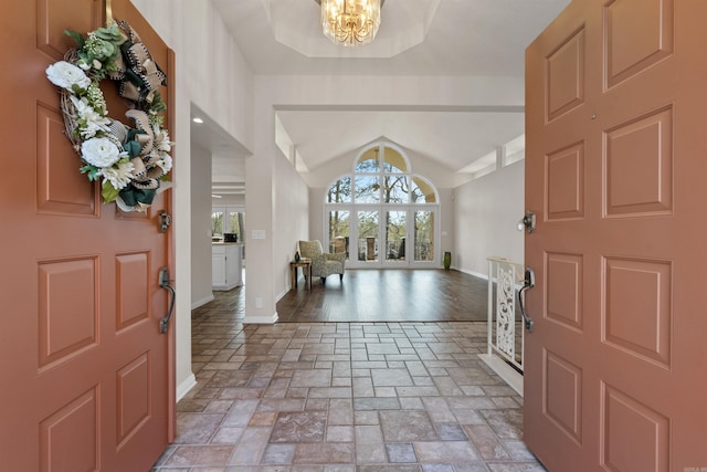 foyer entrance featuring a notable chandelier, lofted ceiling, and light hardwood / wood-style flooring