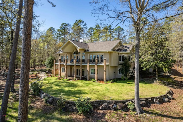 rear view of property with a balcony and a lawn