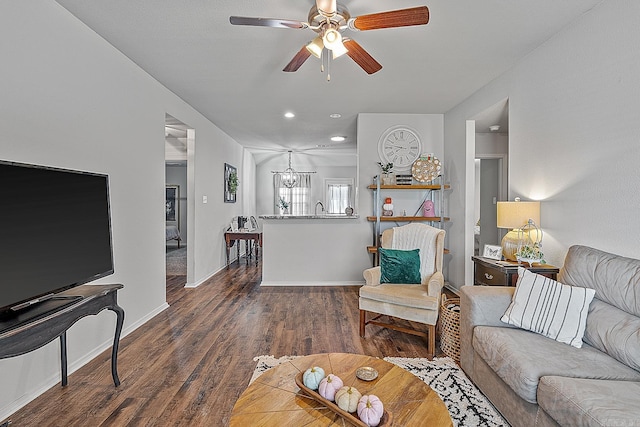 living room with ceiling fan with notable chandelier and dark hardwood / wood-style floors