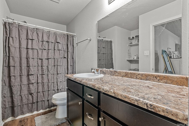 bathroom featuring wood-type flooring, a textured ceiling, vanity, and toilet