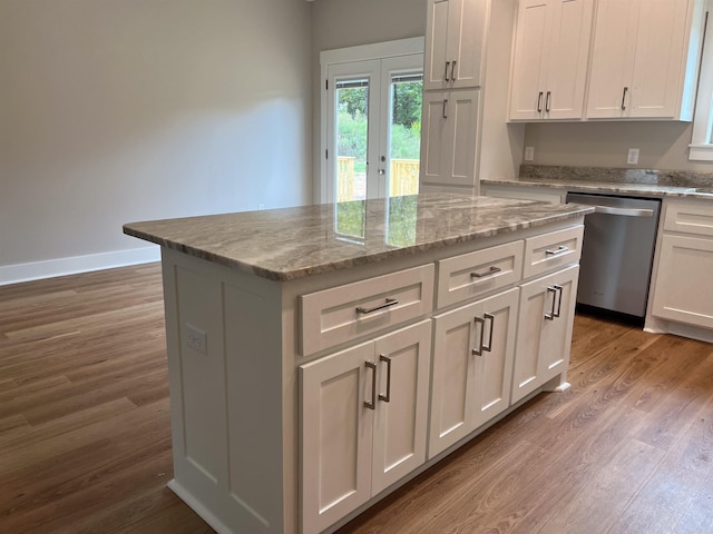 kitchen featuring wood-type flooring, stainless steel dishwasher, white cabinetry, and a center island