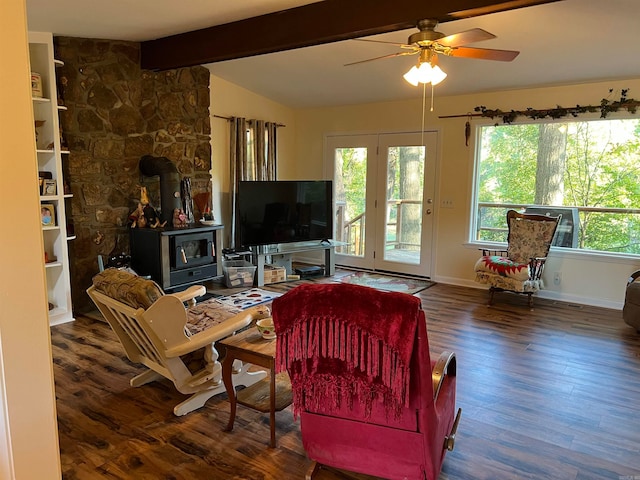 living room with ceiling fan, plenty of natural light, dark hardwood / wood-style flooring, and a wood stove