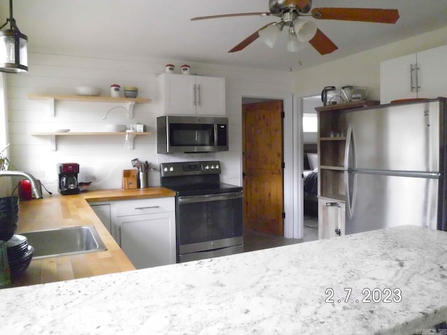 kitchen with butcher block counters, ceiling fan, stainless steel appliances, and white cabinets