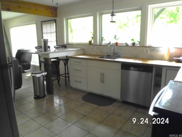 kitchen featuring stainless steel dishwasher, pendant lighting, plenty of natural light, and white cabinets