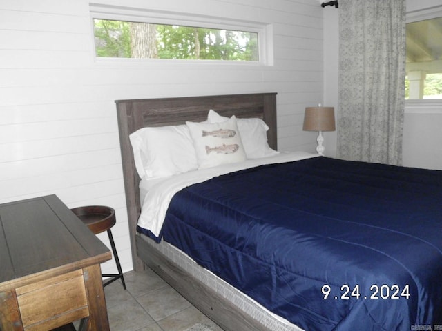 bedroom with wood walls and tile patterned flooring