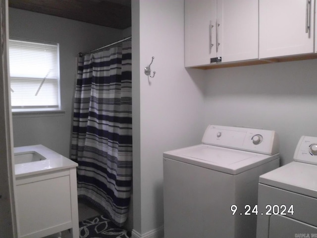 washroom with sink, washer and dryer, and cabinets