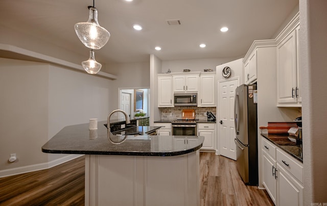 kitchen featuring white cabinets, light wood-type flooring, stainless steel appliances, and hanging light fixtures