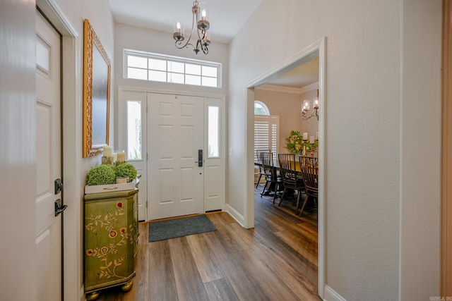 foyer entrance featuring crown molding, an inviting chandelier, and hardwood / wood-style flooring