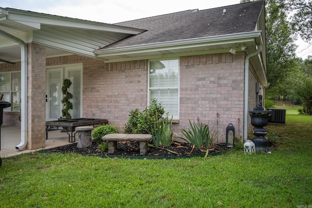 entrance to property featuring a lawn, central AC unit, and a patio area