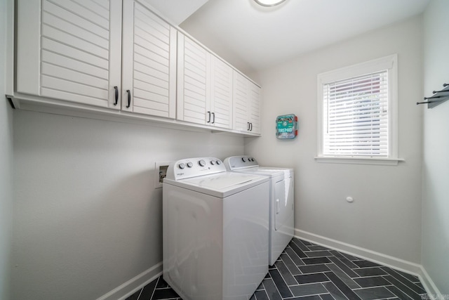 laundry area featuring washer and clothes dryer, dark tile patterned flooring, and cabinets