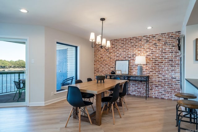 dining room with light hardwood / wood-style flooring, a chandelier, and brick wall