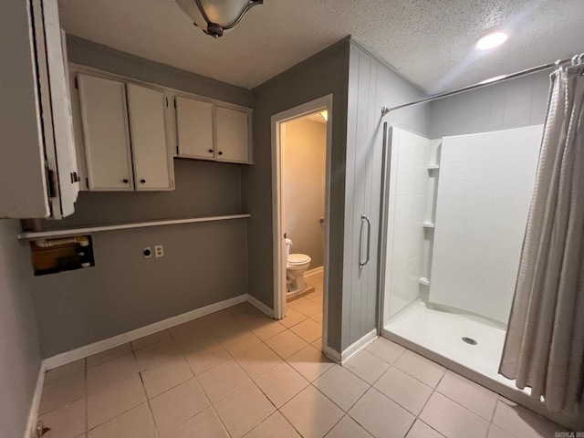 bathroom featuring a textured ceiling, tile patterned flooring, toilet, and curtained shower