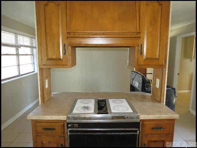 kitchen with crown molding, light tile patterned flooring, and black range with electric cooktop