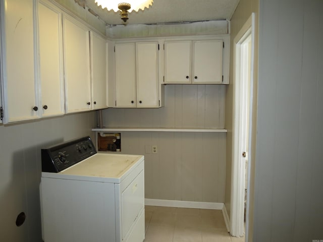 laundry area with washer / clothes dryer, wooden walls, light tile patterned floors, and cabinets