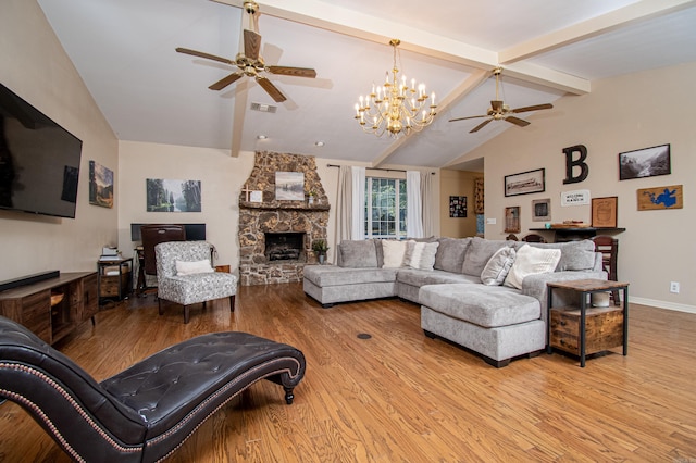 living room featuring vaulted ceiling with beams, a stone fireplace, ceiling fan with notable chandelier, and light hardwood / wood-style floors