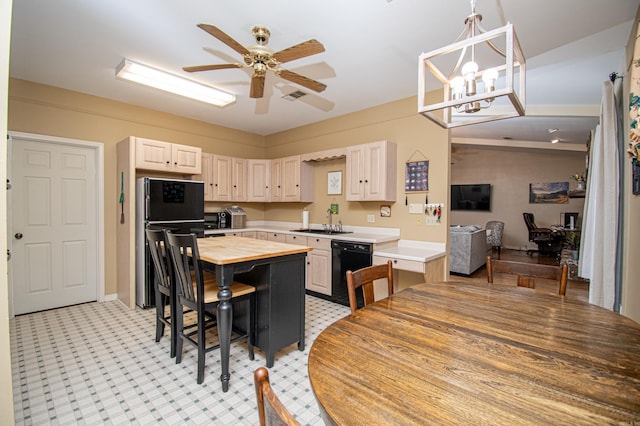 kitchen featuring hanging light fixtures, a breakfast bar, ceiling fan with notable chandelier, black appliances, and sink