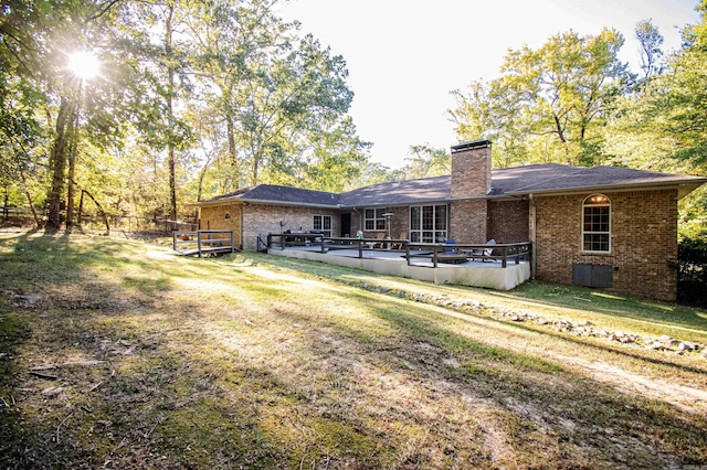 back of property featuring a wooden deck and a lawn