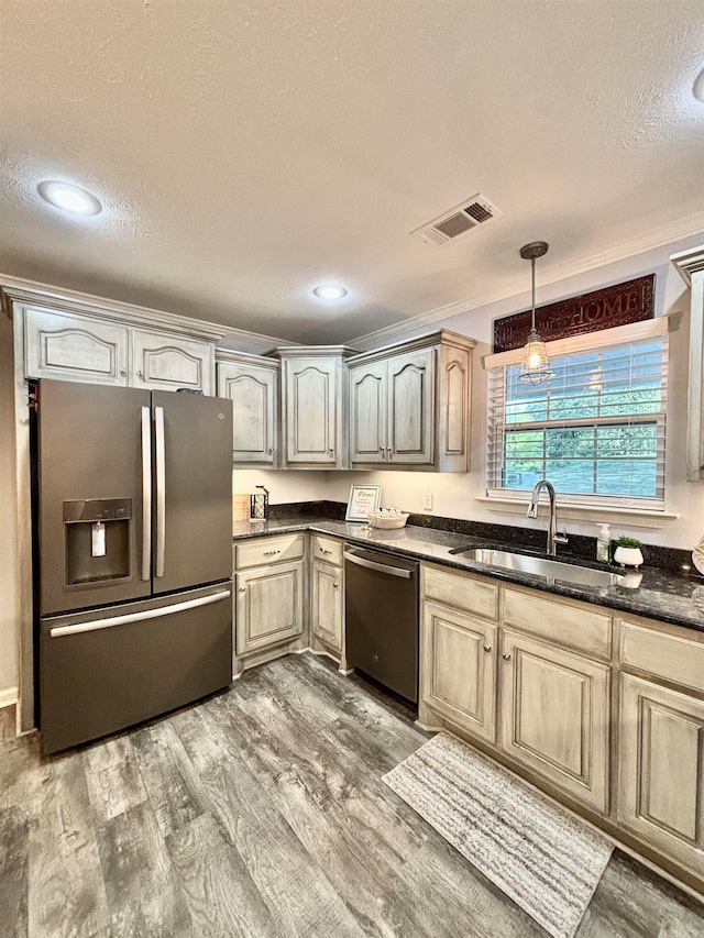 kitchen with appliances with stainless steel finishes, pendant lighting, a textured ceiling, hardwood / wood-style flooring, and sink