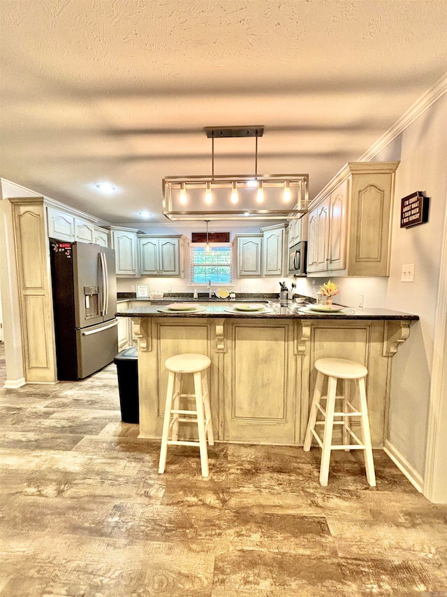 kitchen with hardwood / wood-style floors, kitchen peninsula, a textured ceiling, stainless steel appliances, and a kitchen bar