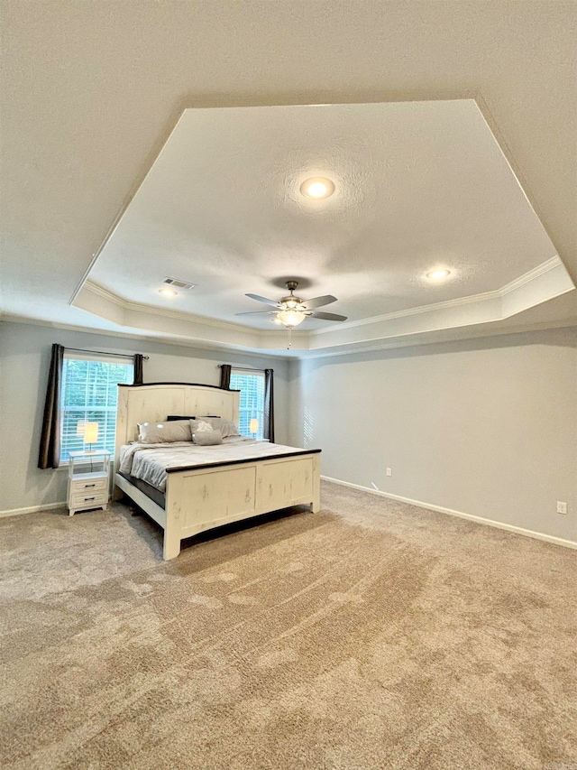 carpeted bedroom featuring a tray ceiling, a textured ceiling, ceiling fan, and crown molding