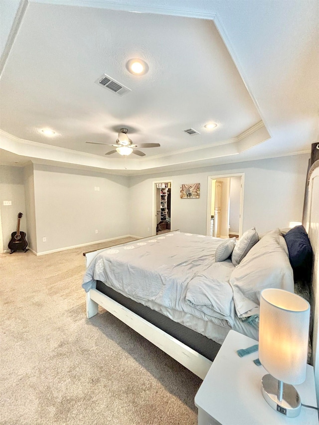 carpeted bedroom with ornamental molding, ceiling fan, and a raised ceiling