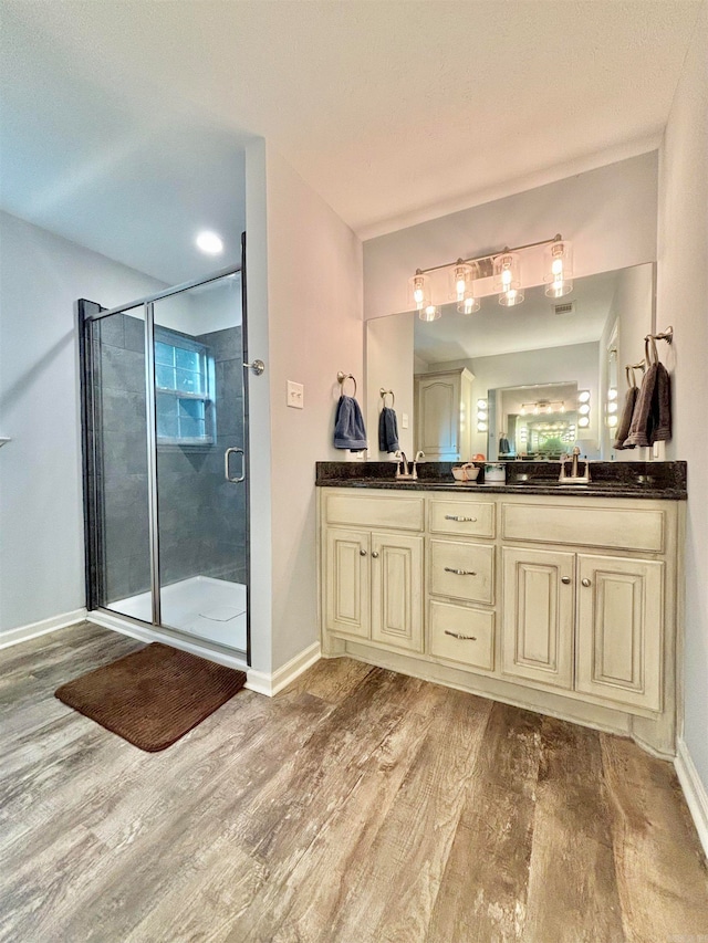 bathroom with hardwood / wood-style floors, a shower with door, and vanity