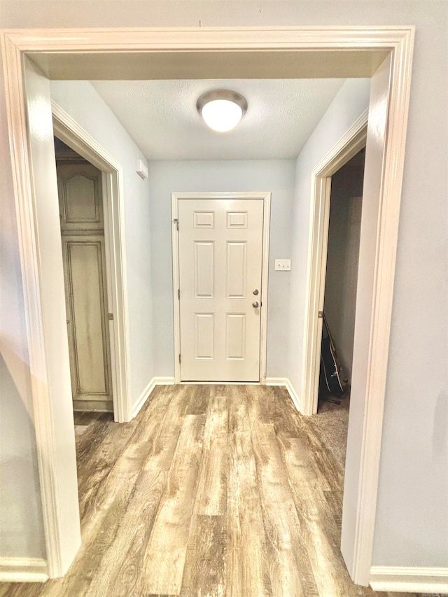 hallway with light wood-type flooring and a textured ceiling