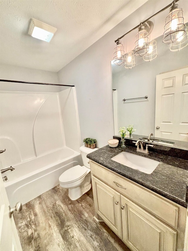 full bathroom featuring vanity, wood-type flooring, a textured ceiling, shower / tub combination, and toilet