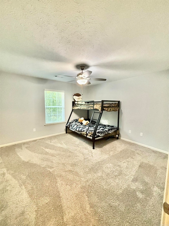 bedroom with a textured ceiling, carpet, and ceiling fan