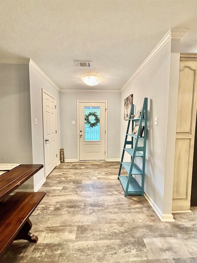 entrance foyer with wood-type flooring, a textured ceiling, and ornamental molding