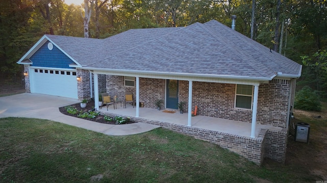 view of front of home featuring covered porch, a front yard, and a garage