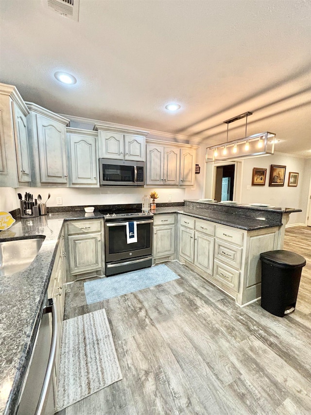 kitchen featuring a textured ceiling, sink, kitchen peninsula, light hardwood / wood-style flooring, and appliances with stainless steel finishes