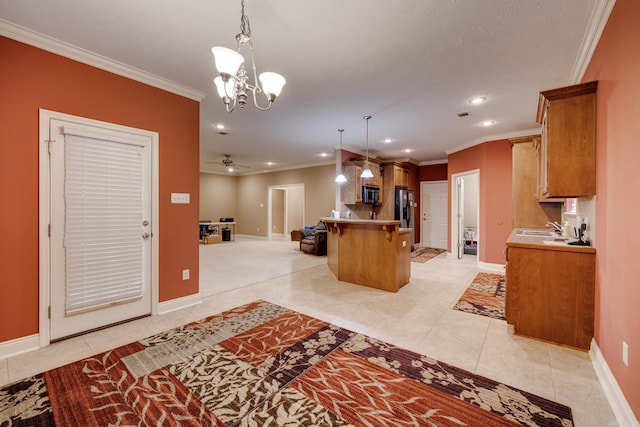 kitchen featuring pendant lighting, ceiling fan with notable chandelier, crown molding, and a kitchen breakfast bar