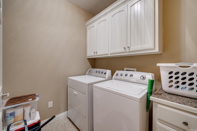 laundry area featuring cabinets, a textured ceiling, washing machine and clothes dryer, and light tile patterned flooring