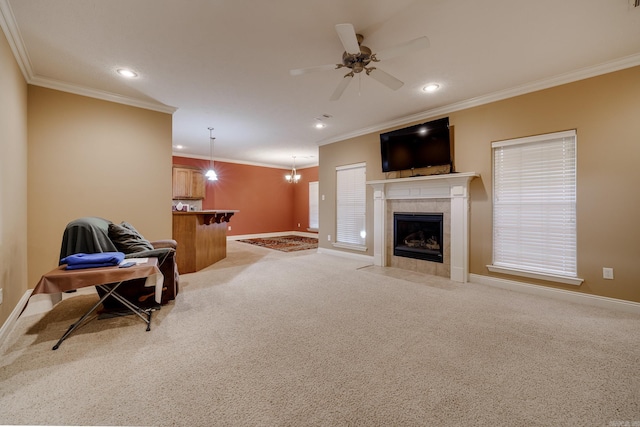 carpeted living room featuring a tiled fireplace, ceiling fan, and crown molding