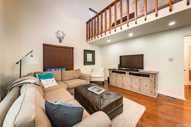 living room with light hardwood / wood-style floors and a towering ceiling