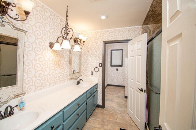 full bath with a sink, double vanity, wallpapered walls, and a notable chandelier