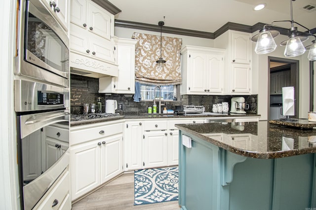 kitchen with stainless steel appliances, dark stone countertops, decorative backsplash, pendant lighting, and light wood-style flooring