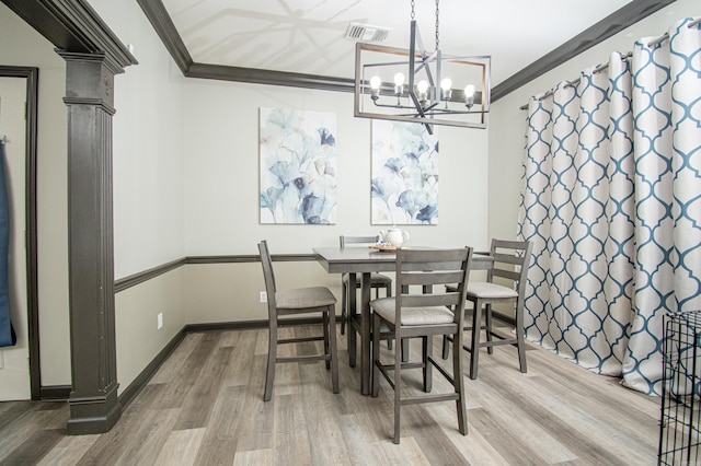 dining area with visible vents, crown molding, wood finished floors, and an inviting chandelier