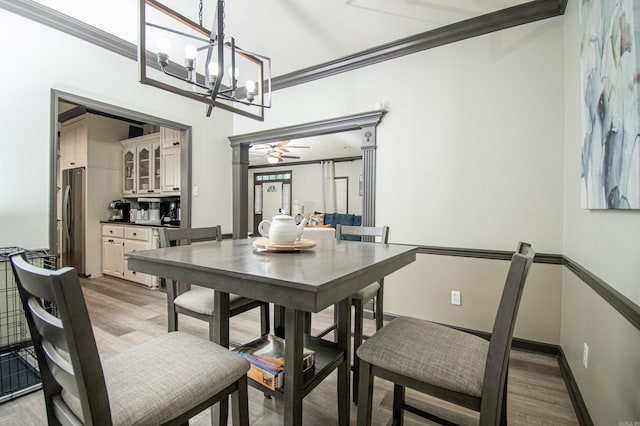 dining space featuring ceiling fan with notable chandelier, light wood-style floors, baseboards, and ornamental molding