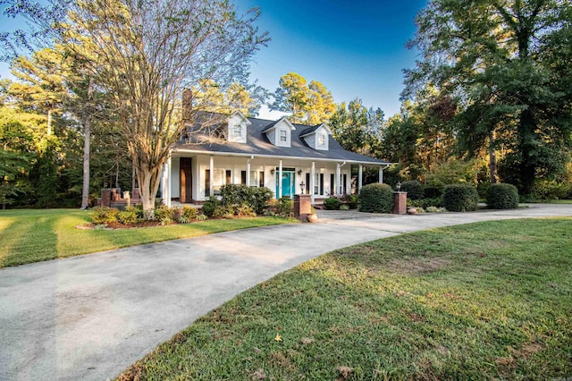view of front of home with concrete driveway, a porch, and a front yard