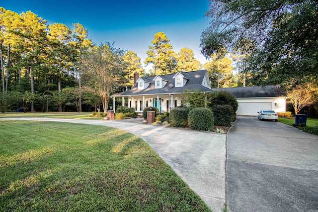 cape cod home featuring a front lawn, a chimney, covered porch, and curved driveway
