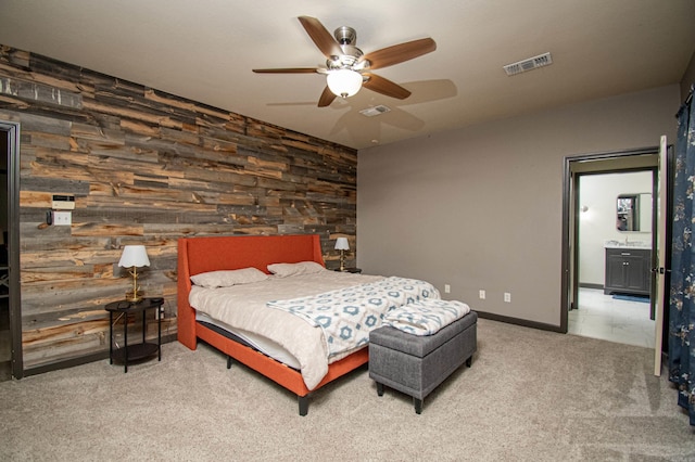 carpeted bedroom featuring an accent wall, wooden walls, ceiling fan, and visible vents
