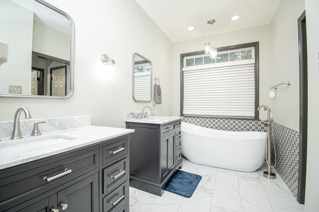 bathroom featuring marble finish floor, a sink, wainscoting, and a freestanding bath