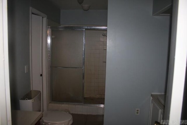 bathroom with vanity, toilet, and a shower with door